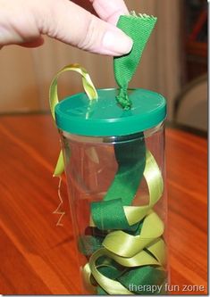 a hand is holding a green ribbon in a glass jar