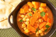 a stew with carrots, chickpeas and cilantro in a black bowl