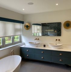 a large bathroom with two sinks and a bathtub in the middle, along with a window