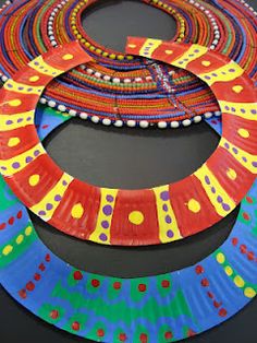 three different colored paper plates are stacked on top of each other, with dots and circles painted on them