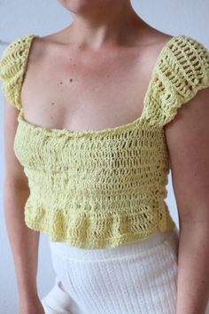 a woman wearing a yellow crochet top