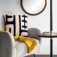 a living room with a chair, round mirror and black and white throw pillow on it