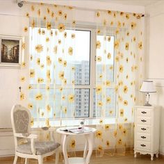 sunflowers are on the sheer curtains in this living room with white furniture and wooden flooring