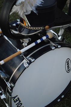 a close up of a drum set on the ground with feathers in it's mouth