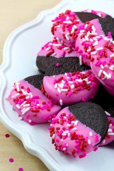 pink and black cookies with sprinkles on a white plate