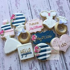 decorated cookies are arranged on a white wooden surface with pink and blue accents, such as baby's names