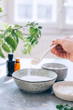 a person holding a spoon over a bowl filled with oatmeal and milk