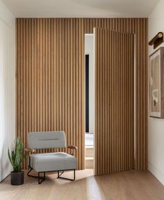 a living room with wooden slats on the wall and a chair next to it