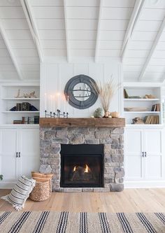 a living room with a fire place and bookshelves on the wall above it