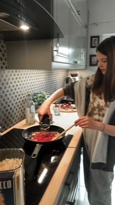 a woman standing in front of a stove cooking food on top of a frying pan