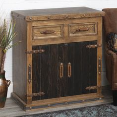 a wooden cabinet sitting next to a chair and potted plant on top of a rug