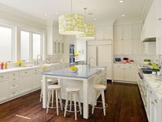 a large kitchen with white cabinets and blue counter tops on the island in front of two stools