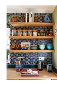 the shelves in this kitchen are filled with dishes and coffee mugs on top of them