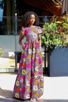 "Shop our new collection of African print designs. Safiyah is a vibrant mix of Summer bursting colours handmade with 100% cotton fabric. Designed to give elegance in a full flare design, fitted to the waist, measuring 60\", model wearing UK10/US6. Product Detail Fit and Style  Product Shape: Maxi Dress Length: 60\" Fit: fitted at waist Style: Flare Sleeve No added Stretch  Fastener: Yes, back Zipper Pocket: Yes  Inner Lining: No Care Instructions  Recommended for Handwashing and Dry clean only." Multicolor Cotton A-line Midi Dress, Printed Cotton Purple Dresses, Purple Printed Cotton Dress, Purple Cotton Printed Dresses, Vibrant Short Sleeve Maxi Dress With Floral Print, Vibrant Pink Dress With Bold Print, Multicolor Floral Print Cotton Maxi Dress, Cotton Dresses With Vibrant Patterned Print, Multicolor Cotton Maxi Dress With Floral Print