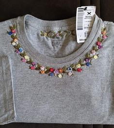 a t - shirt with flowers on it is sitting on the floor next to a price tag