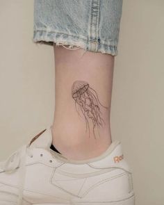 a woman's ankle with a small jellyfish tattoo on her left side ribcage