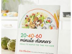 a cookbook sitting on top of a counter next to vegetables and other food items