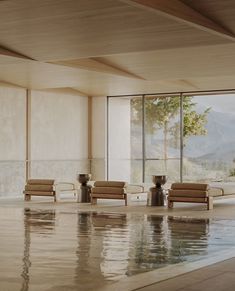 an indoor swimming pool with two chairs and a large window overlooking the mountain range in the background