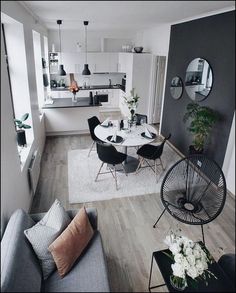 a living room filled with furniture next to a kitchen and dining room table on top of a hard wood floor