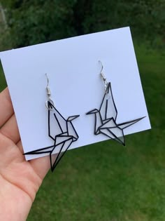 a pair of black origami bird earrings sitting on top of a white card