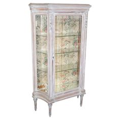 an antique white china cabinet with floral wallpaper on it's glass doors and drawers