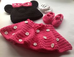 three crocheted items are sitting on a table together, one is black and the other is pink