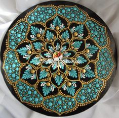 a black plate with blue and gold designs on it's sides, sitting on a white cloth