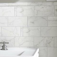 a white sink sitting under a faucet on top of a bathroom counter next to a tiled wall