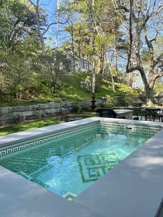 an empty swimming pool in the middle of a yard with tables and chairs around it