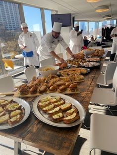 several chefs are preparing food at a long table with plates and bowls on the table