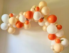 an arch made out of balloons with tomatoes on them and oranges hanging from the top