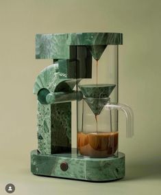 a green marbled coffee maker with liquid pouring out of it's glass cup