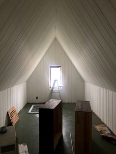 an empty room with white walls and wood flooring in the center, there is a ladder up to the window