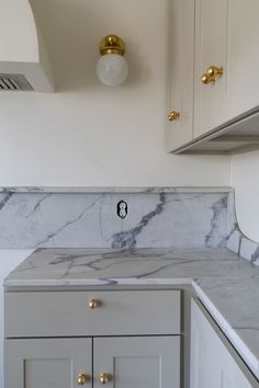 a kitchen with marble counter tops and gold knobs