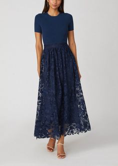 a woman is wearing a blue dress with floral lace on the bottom and side, while she