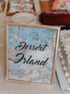 a dessert island sign sitting on top of a table next to a plate and cake