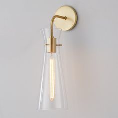 a light that is on the wall next to a glass vase with an object in it