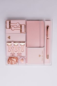 the contents of a pink planner and pen in a clear box with gold accents on it