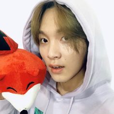 a person holding a stuffed animal in front of their face and wearing a hoodie