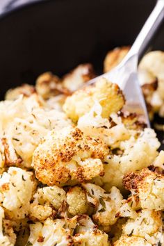 cauliflower being cooked in a skillet with a spoon