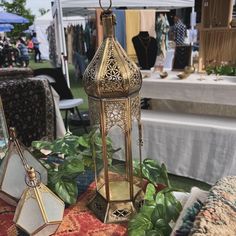 a gold lantern sitting on top of a rug next to other items and plants in front of a tent