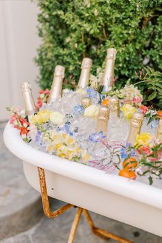 a bath tub filled with lots of bottles of champagne and flowers on top of it