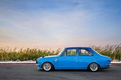 an old blue car parked in a parking lot