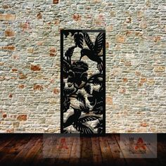 an iron screen with birds and flowers on it in front of a brick wall, against a wooden floor