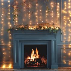 a fireplace with christmas lights on the mantle and around it is a blue painted mantel