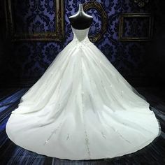 a white wedding dress on display in front of a blue wall