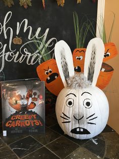 a pumpkin decorated like a bunny with an angry carrot on it next to a book