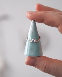 a person holding a ring in their hand with a small cone on it's side