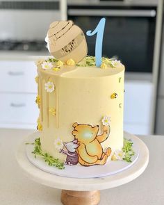 a winnie the pooh birthday cake is decorated with flowers and an icing number one