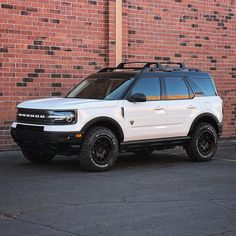 a white suv parked in front of a brick wall